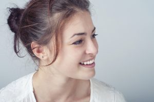 Model with Messy Hair Bun Smiling Away From Camera