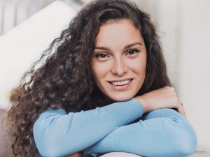 Young Woman with Dark Curly Hair Resting Her Chin on Her Crossed Arms Young Woman with Dark Curly Hair Resting Her Chin on Her Crossed Arms