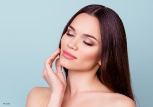 Woman with Bare Shoulders and Eyes Closed Holding her Hand to her Smooth Face Woman with Bare Shoulders and Eyes Closed Holding her Hand to her Smooth Face