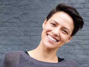 Woman with Black Pixie Cut Hair Smiling and Titling Head to the Side